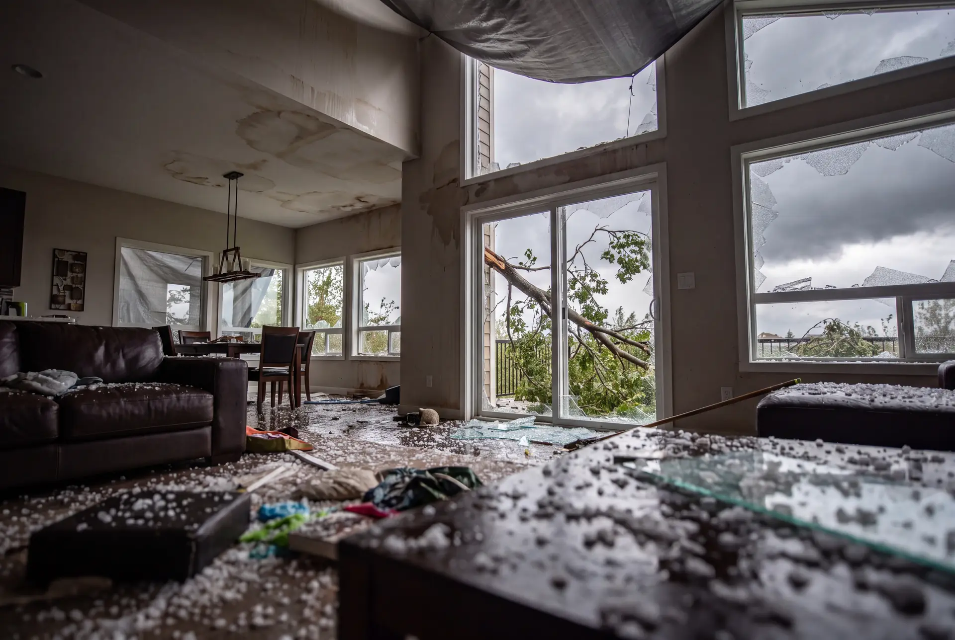 Storm damage to a home, with broken windows, hail, a damaged roof, or a fallen tree